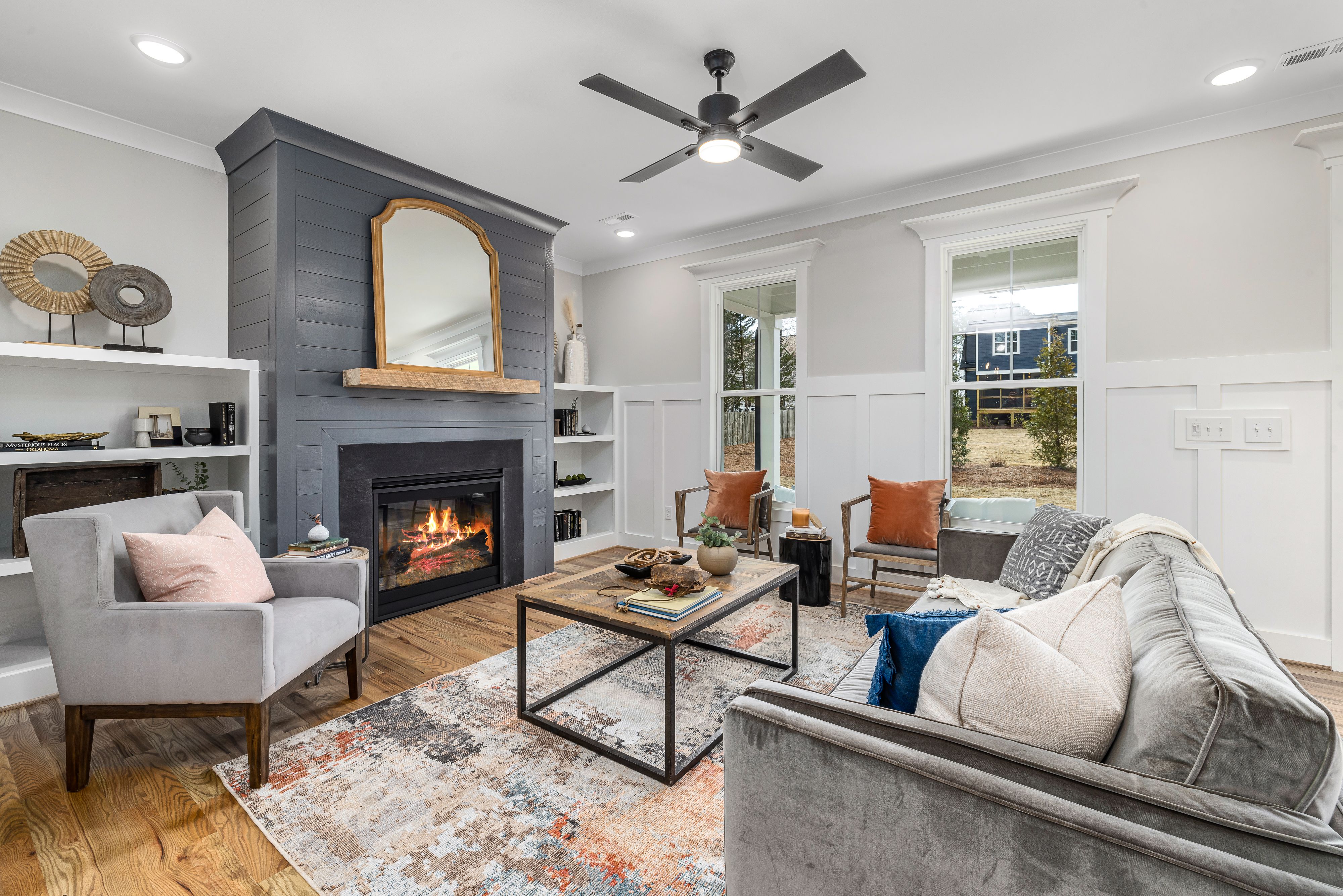 Living room with neutral upholstered seating, wood furniture and a charcoal fireplace.